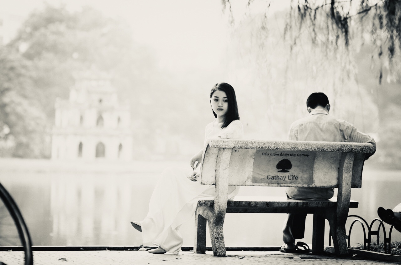 Woman and man on a bench, facing away from each other as if in a lover's quarrel.
