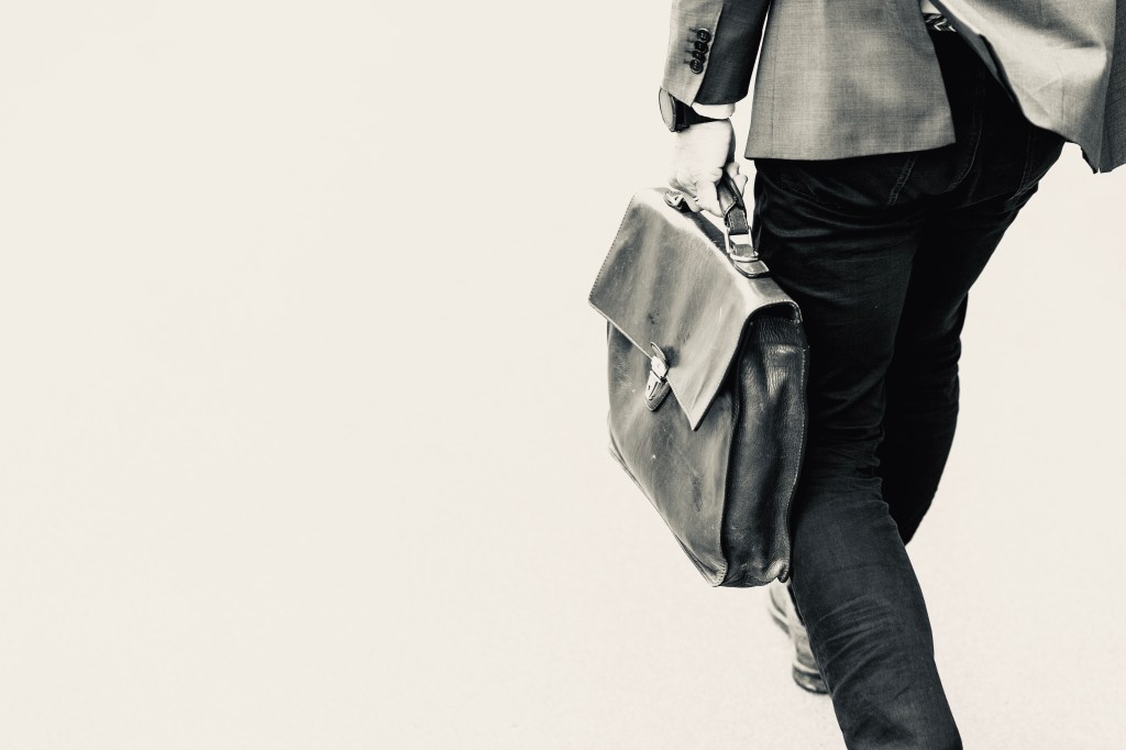 A man carrying a briefcase walking away.